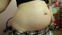 pudgy girl playing with her belly in a skirt